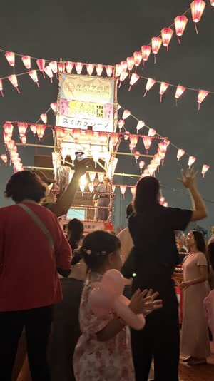 Ring of dancers in yukata seen from behind, arms raised in the same gesture, summer night festival, lantern glow on cotton fabric, gentle motion visible