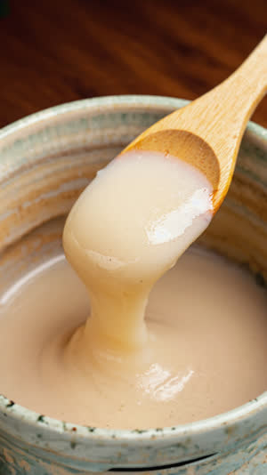 Macro close-up of rice koji grains covered in fine white mold filaments in a white ceramic dish, extreme texture detail, soft top light, shallow depth of field