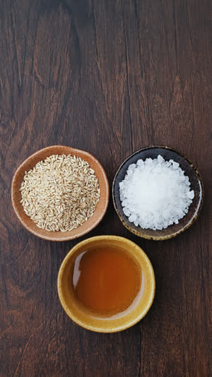 Fresh green cucumber half buried in beige rice bran mash, close-up at an angle, strong color contrast, moist bran texture, natural kitchen light