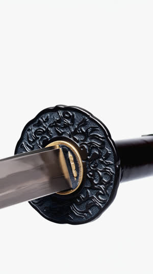 Side view of clay-coated katana blade, thin coat near the edge and thick sculpted clay on the body, textured grey over dark steel, precise studio light