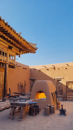 Traditional forging hall prepared for a public demonstration, clay furnace at center, wooden viewing area, tools laid out neatly, quiet anticipation