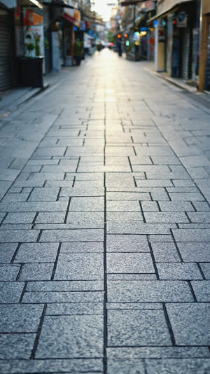 Low-angle close-up of an immaculate Japanese shopping street pavement, clean stone texture stretching into soft bokeh, gentle afternoon light