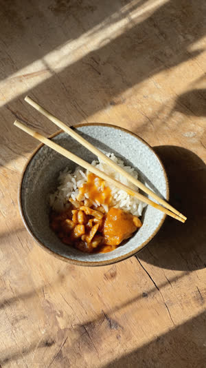 Finished donburi bowl with chopsticks laid neatly across the top, quiet gratitude implied, soft afternoon light on wood