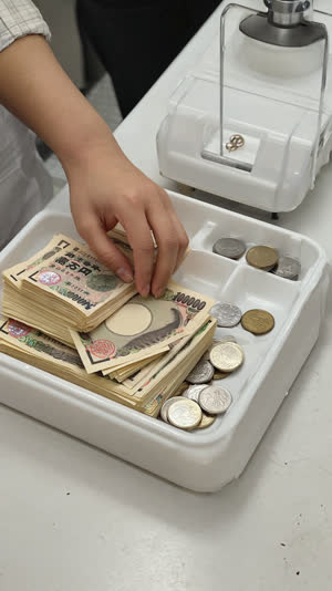 Hand placing yen banknotes and coins on a cashier tray in Japan, exact payment moment, clean counter and soft light
