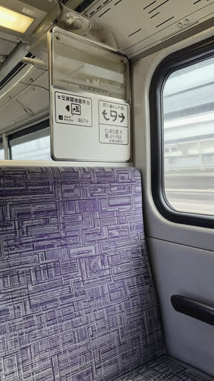 Priority seat sign and distinctive seat fabric on a Japanese train, informative close-up, clean daylight through window
