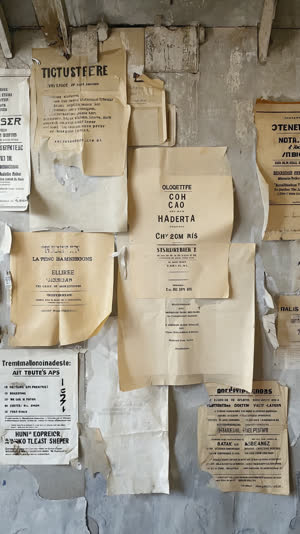 Station notice board with layered etiquette posters old and new, paper textures and tape marks, documentary feel