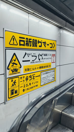 Escalator entrance safety sign in a Japanese station, clean graphic close-up, bright even light