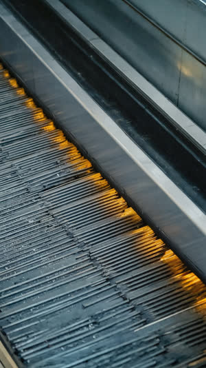 Macro of escalator step grooves and moving handrail belt, industrial texture, shallow depth of field, warm highlights
