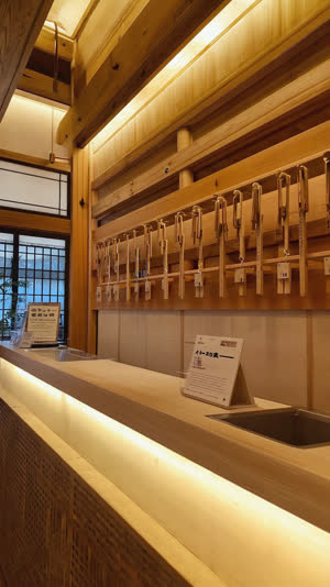 Onsen reception counter with wooden key racks and a printed notice, warm interior light, shallow depth of field
