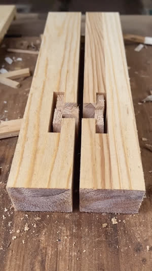 Extreme close-up of two pieces of pale timber cut with interlocking tongues and slots fitted together, precise hand-cut surfaces, workshop light, photorealistic documentary…