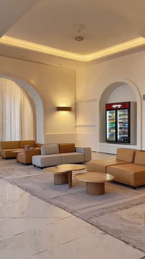 Wide shot of a modern sento lobby with lounge seating, drink refrigerator, warm minimalist renovation, welcoming atmosphere, evening interior light