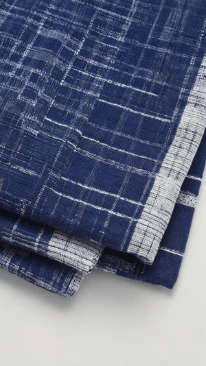 Macro shot of folded cotton tenugui towel with crisp creases, traditional Japanese pattern, clean fabric texture, soft diffused light