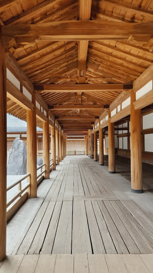 An empty wooden temple veranda facing a dry rock garden, worn smooth boards in soft light, inviting quiet contemplation, photorealistic documentary photograph, natural soft…
