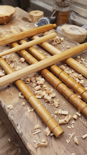 Artisan workbench with rows of handcrafted wooden chopsticks and fresh shavings, natural wood textures, workshop window light