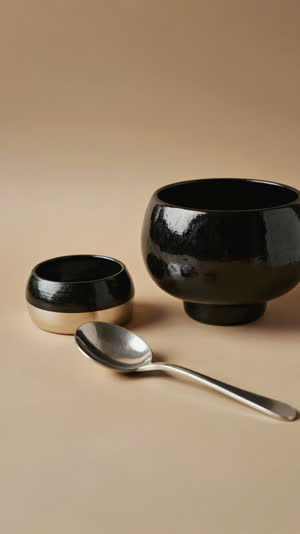 Japanese lacquer bowl and Korean stainless spoon arranged side by side as equals, symmetrical still life, neutral elegant backdrop, soft light