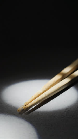 A single pair of pale cedar chopsticks in a beam of soft light, straight flawless grain glowing, dark background, minimal reverent still life