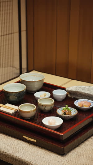 Japanese meal tray viewed at a low respectful angle, orderly bowls in quiet harmony, serene composition, muted tones, gentle window light