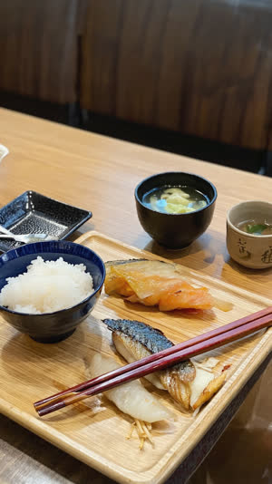 Set-meal teishoku on a plain diner table with chopsticks and a cup of green tea, casual Japanese restaurant atmosphere, honest documentary style
