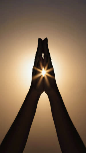 Silhouette of two hands pressed together in gratitude against warm backlight, symbolic and cinematic, gentle lens glow