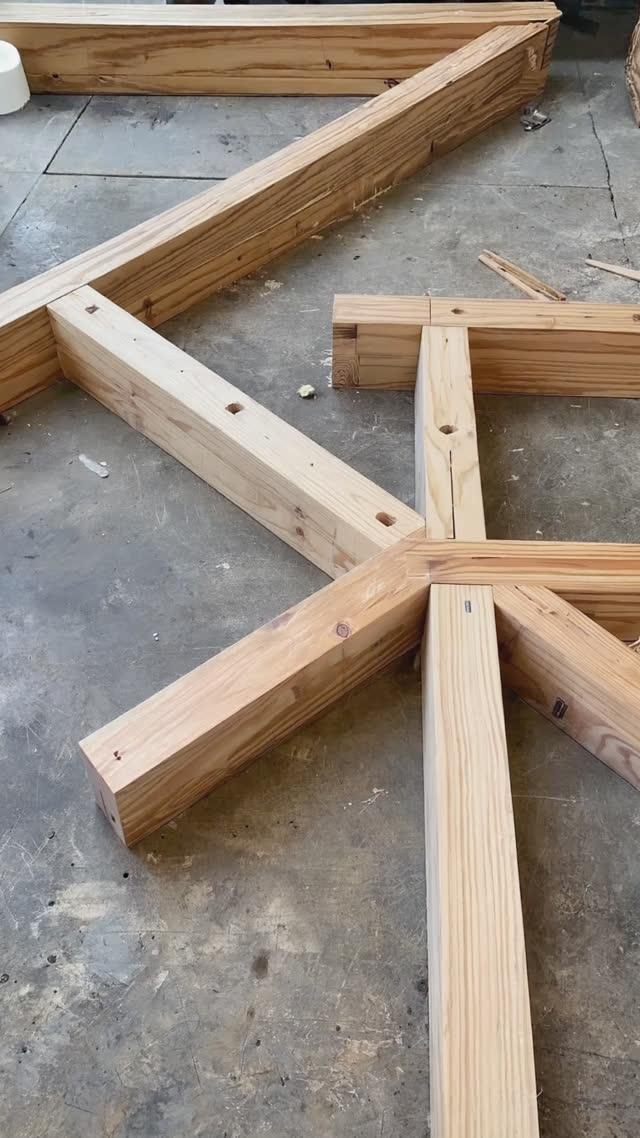 Disassembled wooden structural members with visible cut joints laid out on a workshop floor, ready to be reassembled, photorealistic documentary photograph, natural soft light,…