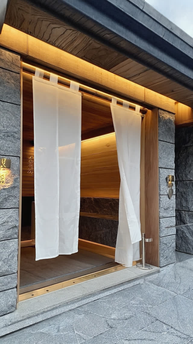 Freshly renovated bathhouse entrance with crisp new noren curtain on a historic facade, blend of modern design and old architecture, bright welcoming light