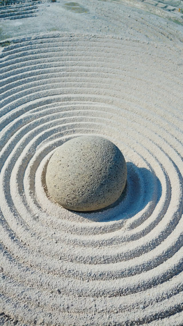 A single weathered rock set in a field of raked white gravel with concentric ripple patterns around it, generous empty space, photorealistic documentary photograph, natural soft…