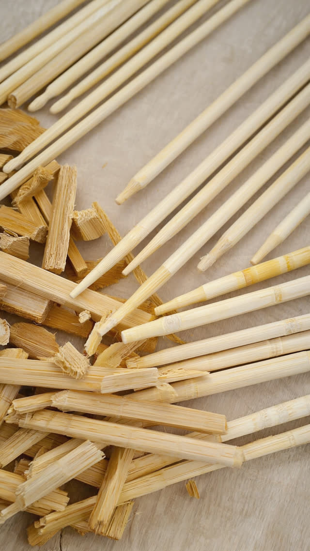 Rows of freshly planed white cedar chopsticks lined up beside rough offcut scraps, transformation from waste to product, macro wood grain
