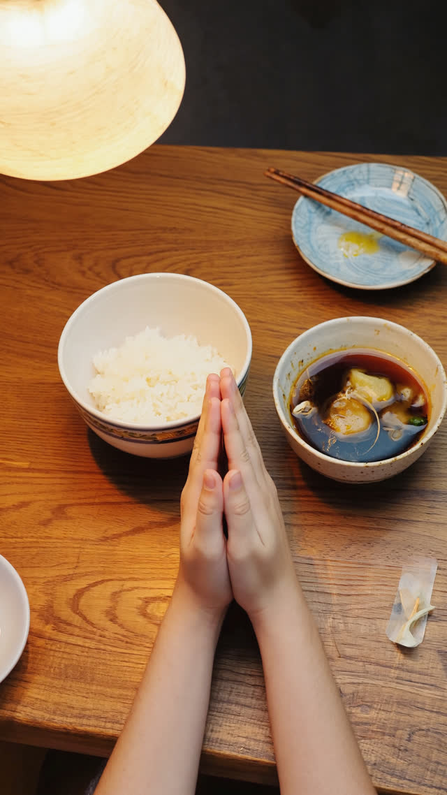 First-person point of view looking down at a finished Japanese meal — empty rice bowl, miso soup bowl, small plates with only traces of food, chopsticks resting together on a…