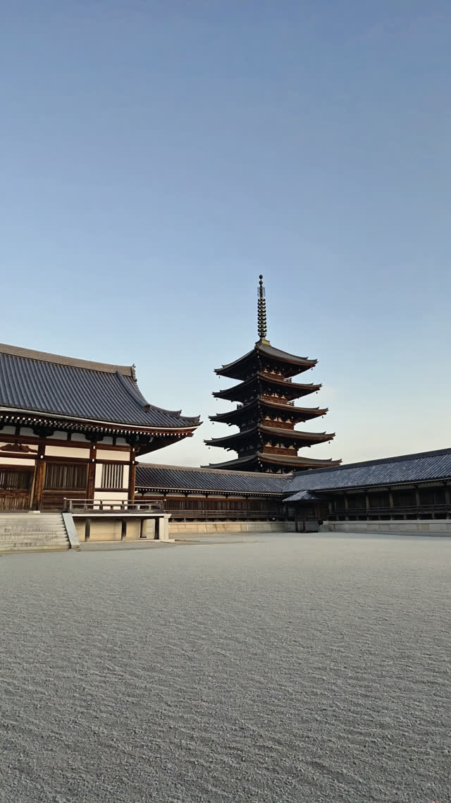 An ancient Japanese temple hall and five-story pagoda standing in an open gravel courtyard, soft morning light, aged timber and white plaster walls, photorealistic documentary…
