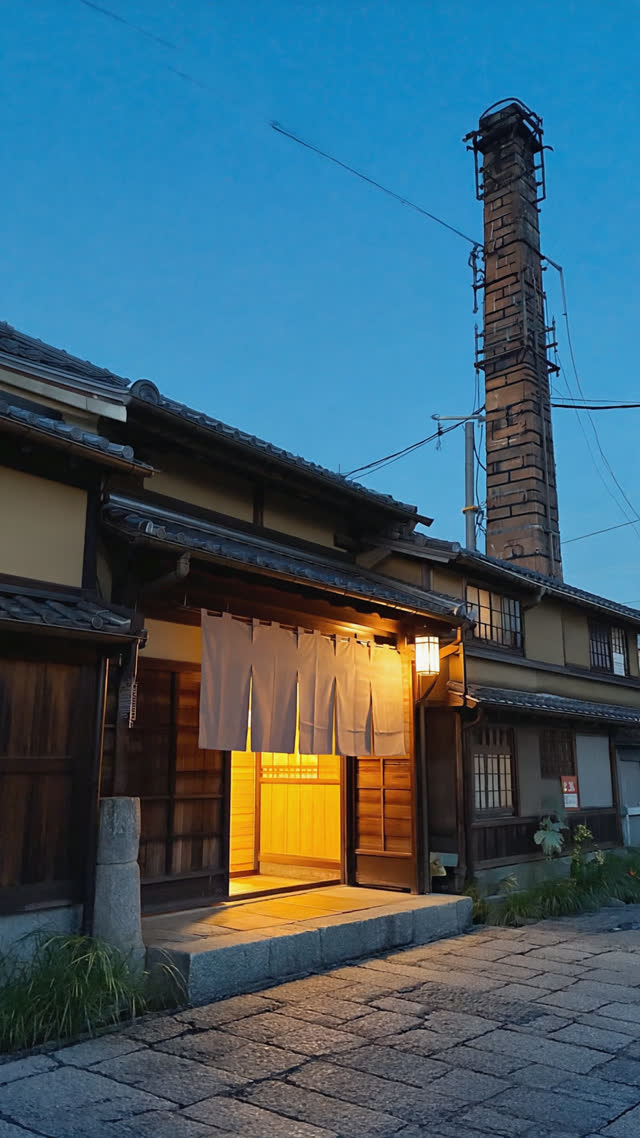 Traditional Japanese public bathhouse exterior at dusk, glowing entrance with fabric noren curtain, tall chimney against twilight sky, warm light spilling out, nostalgic film…